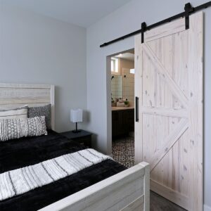 Wood barn door maximizes space in bedroom in this custom ski chalet design built by Big White luxury builder & Kelowna luxury home builder & home designer