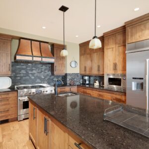 Copper accents in large kitchen design with granite island design built by Big White luxury home builder & Kelowna luxury home builder