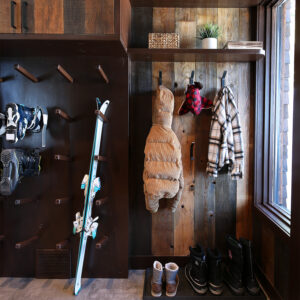 Custom bootroom with barnboard wall cladding and metal hooks, boot dryer